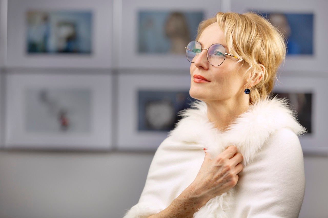 Thoughtful blond woman in fur shrug at opening ceremony of exhibition