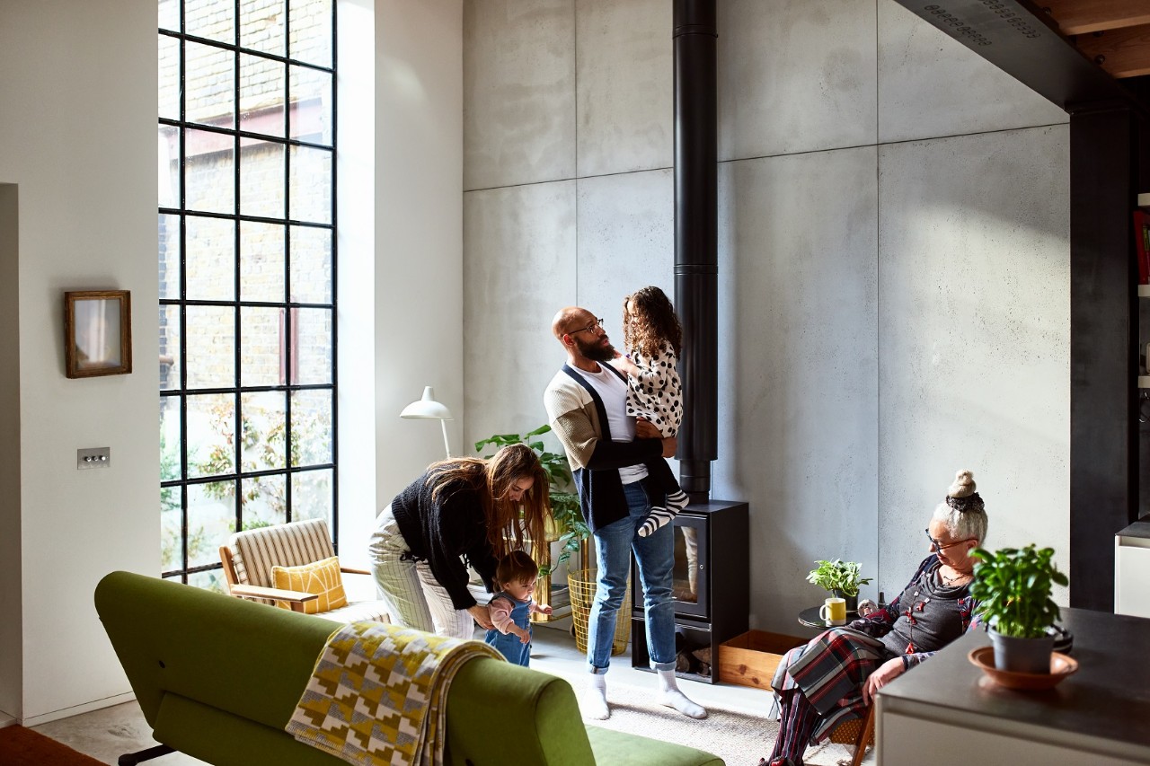 Parents with two children in living room, with grandmother, father holding young girl, mother playing with toddler