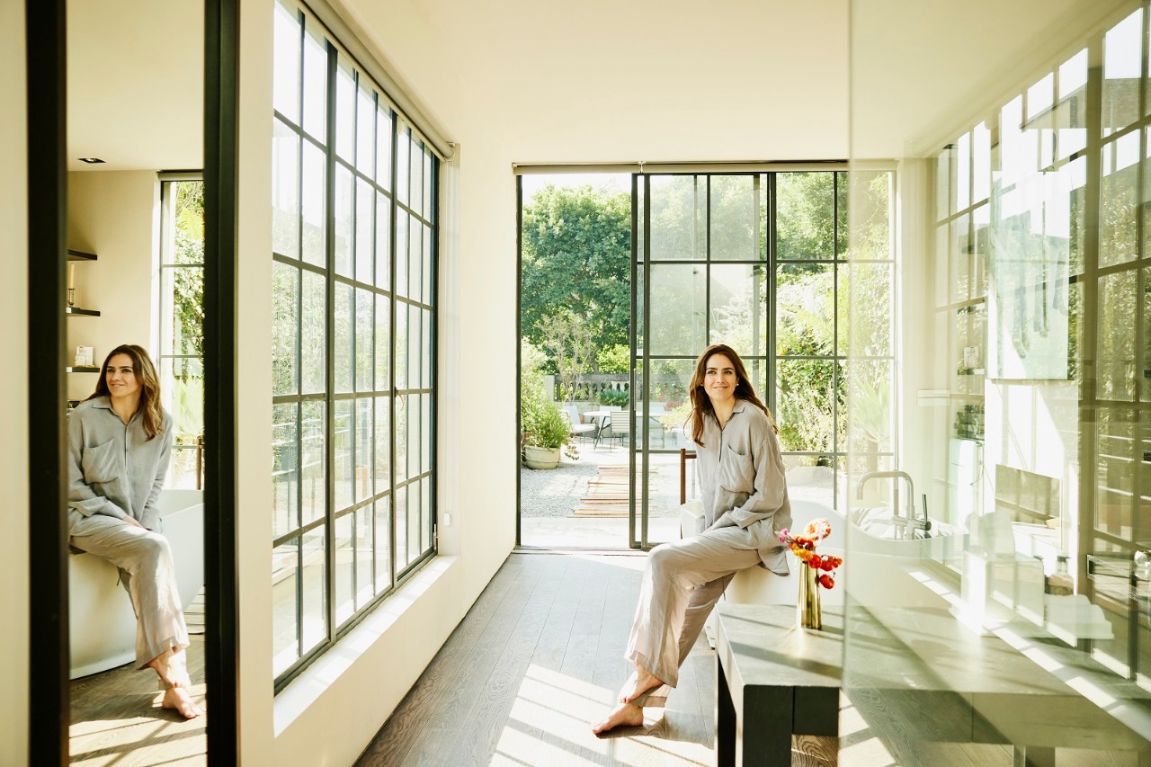 Wide shot of woman relaxing in bathroom of luxury boutique hotel suite during vacation