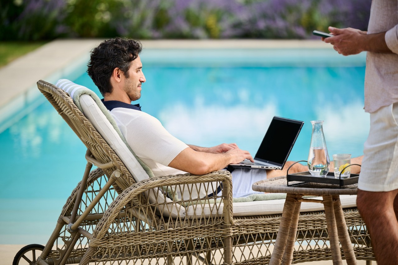 man by pool on laptop